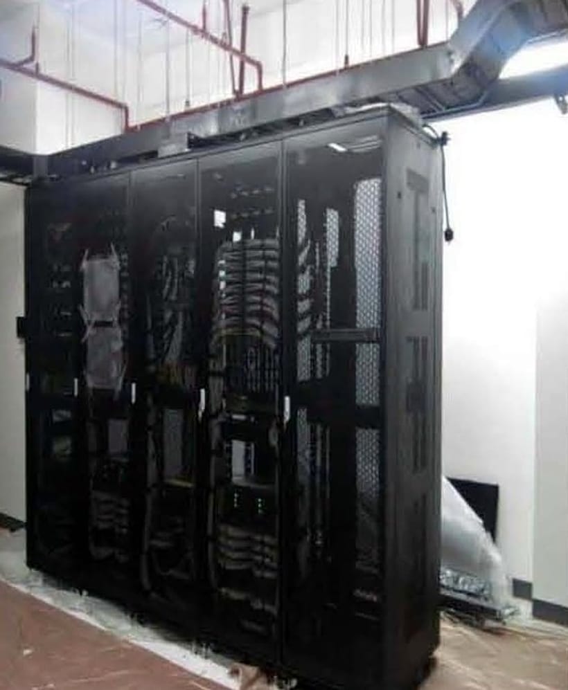Black floor-standing data cabinets being installed in a bare server room