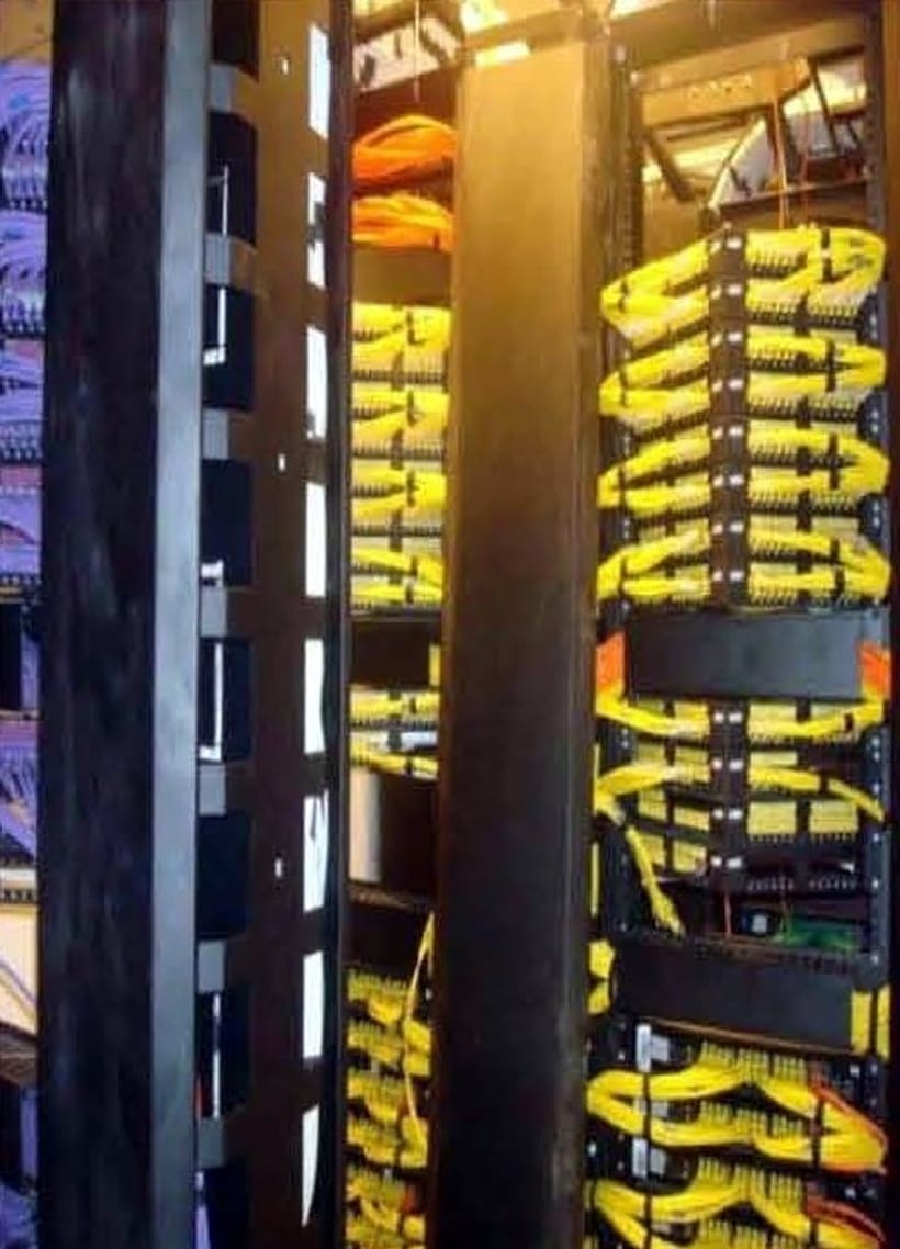 Yellow and blue patch cords routed through vertical cable managers between two racks