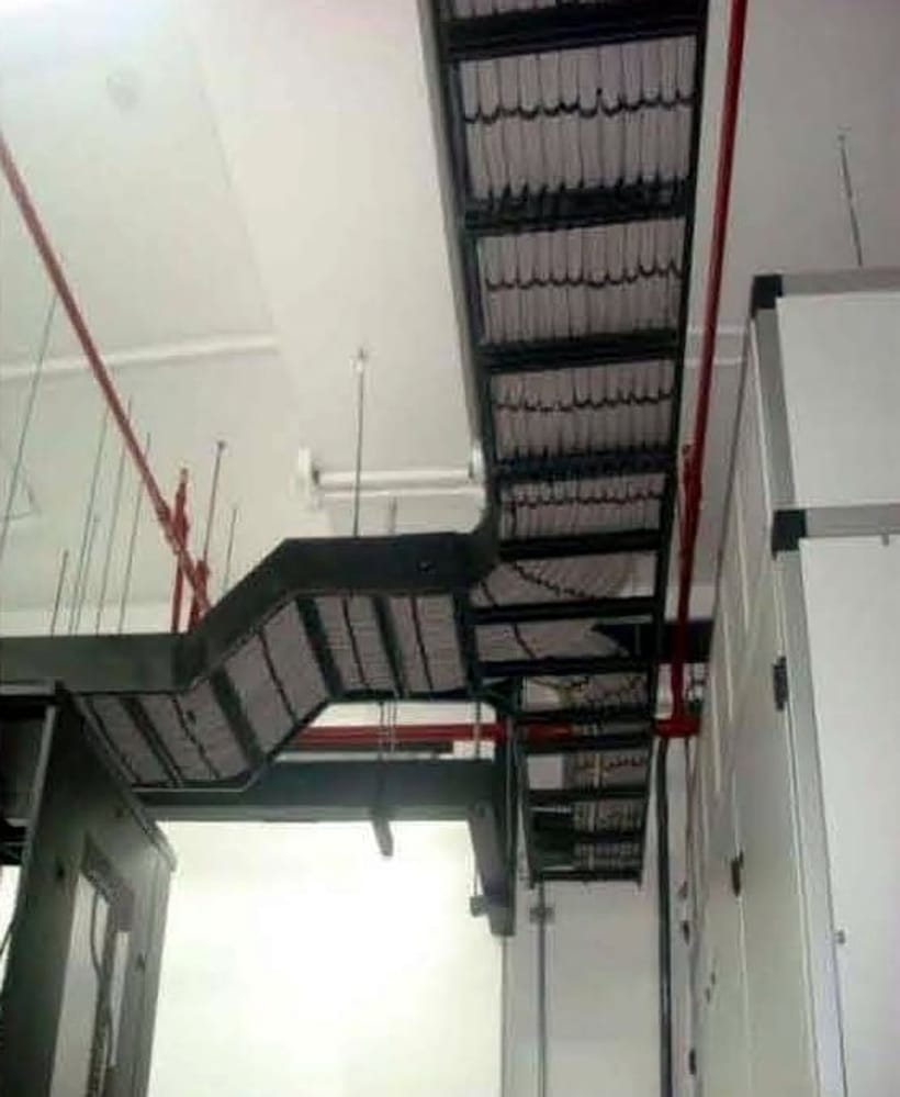 Cable ladder tray running along a ceiling alongside fire-suppression pipework