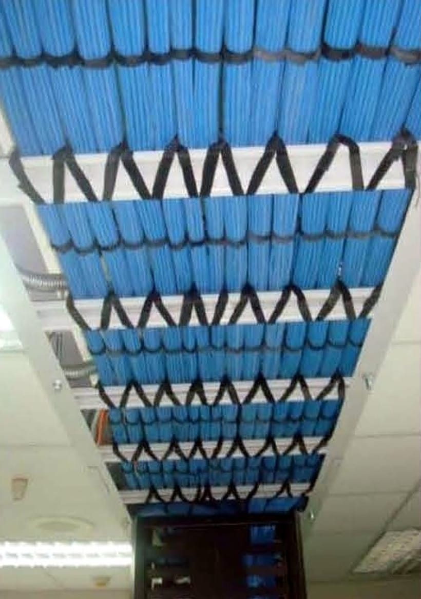 Blue cable bundles fanned out across an overhead basket tray toward a rack