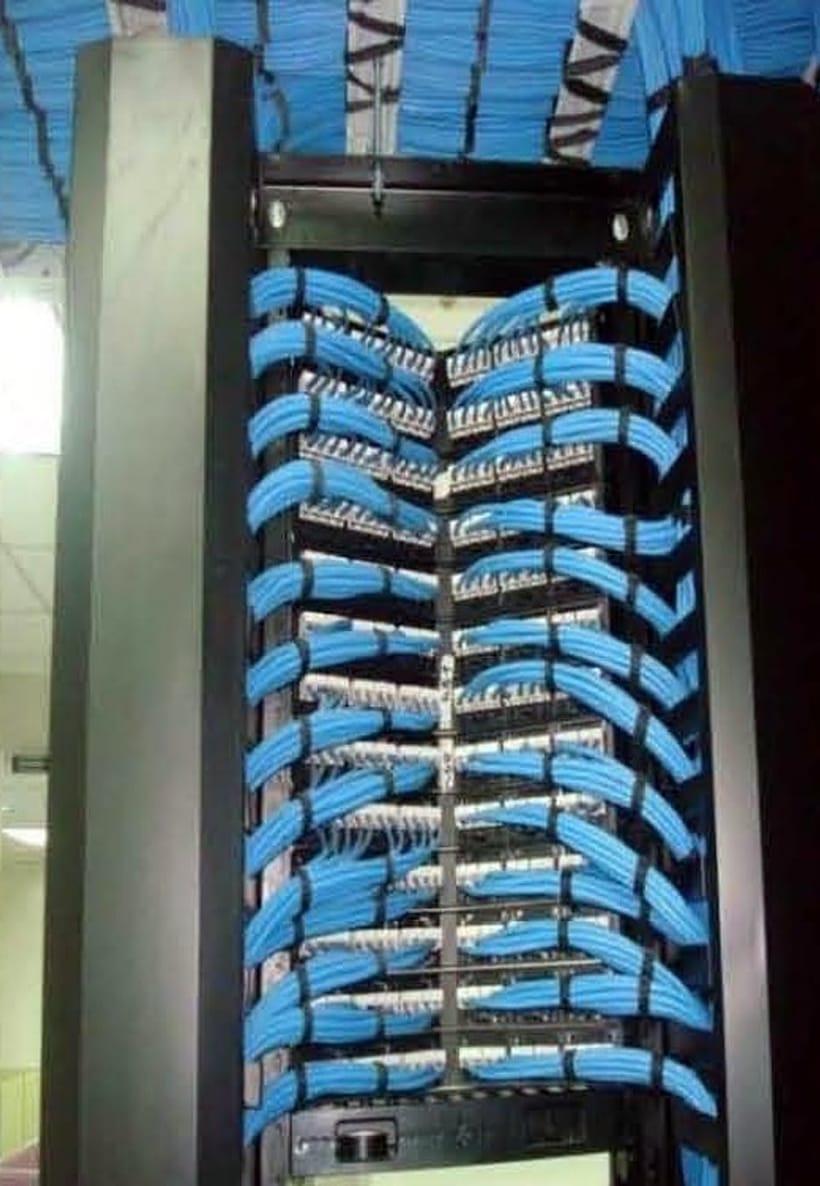 Open-bay telecom rack with blue patch cords dressed into patch panels